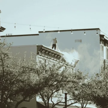 A professional gutter cleaner in Austin, TX, near Round Rock, flushing out gutters and clearing debris from downspouts to ensure smooth water flow and prevent clogs